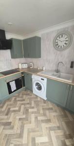 a kitchen with a washing machine and a clock on the wall at Highwood mews in Cleethorpes