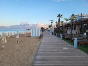 a boardwalk on a beach with chairs and umbrellas at Chryso Apts Protaras in Protaras