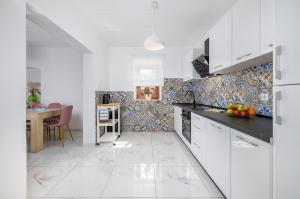 a kitchen with white cabinets and a table with fruits on the counter at Funcic Apartments 1 app in Pula