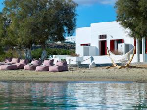 a white house with a hammock next to the water at Unique Milos Suites in Pollonia