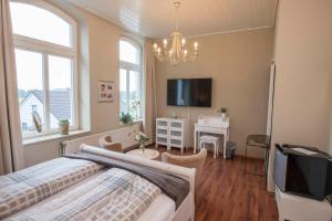 a bedroom with a bed and a tv and windows at Pension Onken in Bockhorn