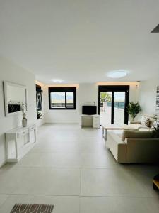 a large white living room with a couch and a tv at Lujosa casa en primera línea playa increibles vistas mar in Laredo