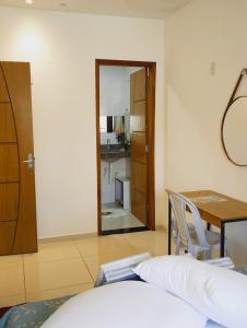 a room with a bed and a table and a mirror at Pousada Aconchego in São Mateus