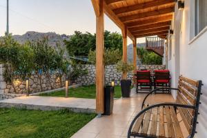 a porch with a wooden bench and a table at Villa Christalia in Kolymbia