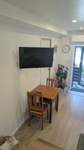 a dining room with a wooden table and a flat screen tv at Rivulet Nook in West Hobart