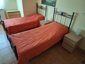 two beds with orange sheets in a room at B&B Nuova Loggia in Fabriano