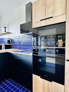 a kitchen with black cabinets and blue tile floors at L'Instant Cottage, Chic et Spa près d'Amboise in Saint-Règle +32 photos
