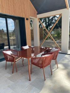 a wooden table and chairs on a patio with windows at L'Instant Cottage, Chic et Spa près d'Amboise in Saint-Règle