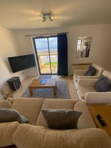 a living room with two couches and a large window at Dolphin Bay Suites in Ardersier