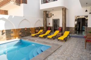 a pool with yellow chairs and a swimming pool at Azure Guest House in Luxor