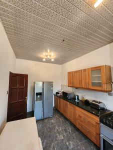 a kitchen with a stainless steel refrigerator and wooden cabinets at S & J Lodge with high speed Starlink WiFi in Tamale