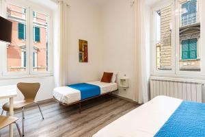 a bedroom with two beds and a table and a desk at Titi Rooms in La Spezia