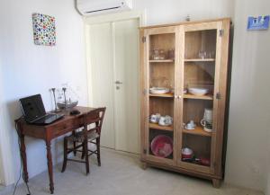 a room with a desk and a wooden cabinet with a laptop at Margarita Studio - Sunset View in Santorini