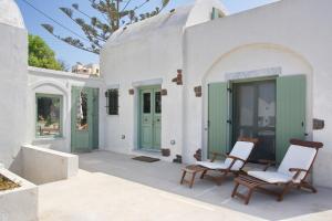 a white house with two chairs and green doors at Margarita Studio - Sunset View in Santorini