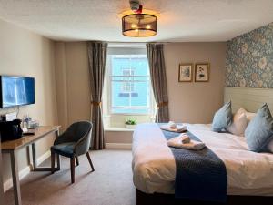 a hotel room with a bed and a desk and a window at The Queen's Head in Alnwick