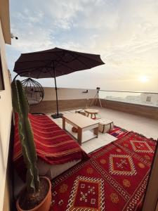 a cactus and a table and an umbrella on a balcony at Swellora Surf Camp Imsouane in Imsouane