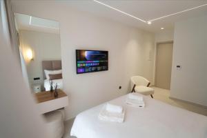 a white room with a bed and a tv on the wall at The Grand Blue Boutique Hotel in Missolonghi +92 photos