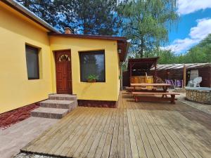 a small yellow house with a wooden deck at Bambusz76 in Zamárdi