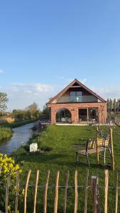 a building with a bench in the grass next to a river at B&B Les Trois Pignons in Diksmuide +14 photos