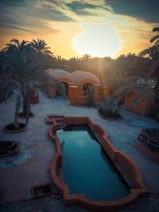 a resort with a swimming pool and palm trees at Nour El wadi in Siwa