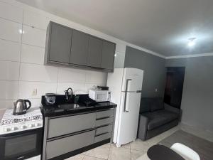 a small kitchen with a sink and a refrigerator at Casa em itapema fácil acesso e bem localizada in Itapema