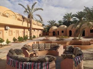 a courtyard with couches and palm trees in a building at Nour El wadi in Siwa
