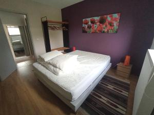 a bedroom with a white bed with a purple wall at Gîte de Thirifays in Chiny