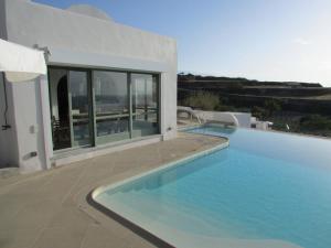 a large swimming pool in front of a house at Margarita Studio - Sunset View in Santorini