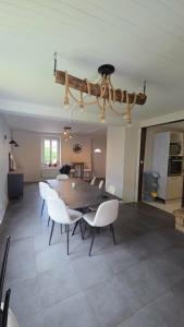 a dining room with a table and white chairs at La liberté des trois petits cochons avec spa in Lalizolle
