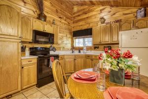a kitchen with wooden cabinets and a table with flowers on it at Mountain View Hot Tub Cabin w Pool Table Romantic in Sevierville +29 photos