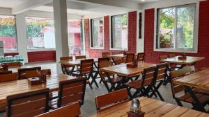 a restaurant with wooden tables and chairs and windows at Lotus Leaf Resort, Murud in Murūd