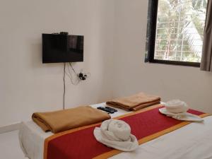 a room with two beds with towels and a television at Lotus Leaf Resort, Murud in Murūd