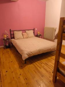a bedroom with a bed with pink walls and wooden floors at La maison de la Loue in Lods