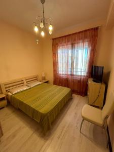 a bedroom with a bed and a chair and a window at Bosco Dream Neptun-Olimp in Neptun