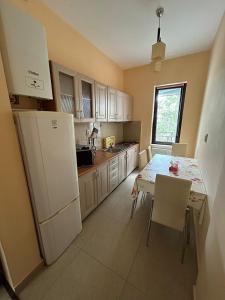 a kitchen with a table and a white refrigerator at Bosco Dream Neptun-Olimp in Neptun