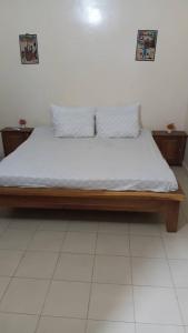 a bedroom with a wooden bed with white sheets and pillows at RÉSIDENCE KFS bTp in Tambacounda