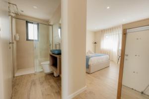 a bedroom with a bed and a bathroom with a shower at Calvário Suites II in Chaves +3 photos