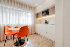 a kitchen with a table and two orange chairs at Calvário Suites l in Chaves