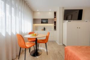 a small dining room with a table and orange chairs at Calvário Suites l in Chaves +3 photos