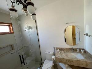 a bathroom with a toilet and a sink and a mirror at Pouso Alvorada in Tiradentes