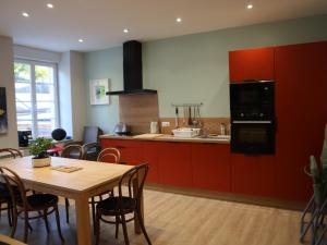 a kitchen with red cabinets and a wooden table with a dining room at Gîte d'artiste in Sainte-Marie-aux-Mines