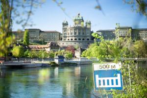 a large building with a sign in front of a river at Dock and Dwell City Appartment in Bern