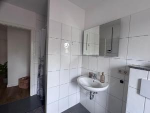 a white bathroom with a sink and a mirror at Stadttor Quartier Puschkinstrasse 58, Lutherstadt Wittenberg in Lutherstadt Wittenberg