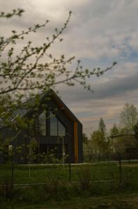 a building in a field with a tree at Wolne Domy in Dominikowice