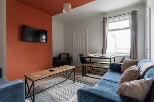 a living room with a blue couch and a table at 3 Bedroom House By Cozy Quarters Property Management Contractors Accommodation Seaham Near Sea in Seaham