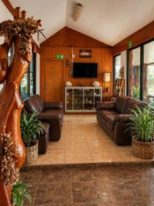 a living room with leather couches and a flat screen tv at Cabañas & Hostal Tojika in Hanga Roa