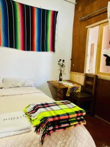 a bedroom with a bed and a window with a colorful blanket at Casa 74 hostel in Comitán