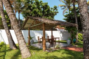 a wooden pergola with a table in a yard at Edelweiss Resort in Mirissa