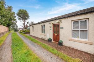 a cottage with a red door on a dirt road at 2 Bed in Aspatria oc-p32645 in Aspatria