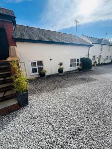 a white building with potted plants in front of it at Vale View Cottages - The Stables in Prestatyn